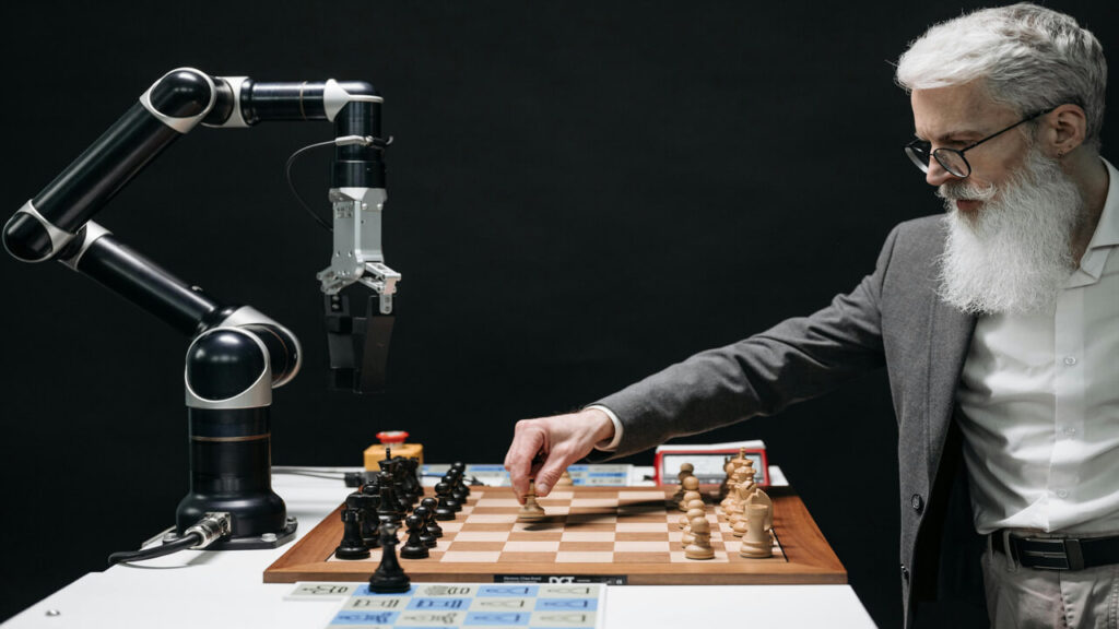 A man strategically moves chess pieces while an AI robot arm assists in a futuristic game