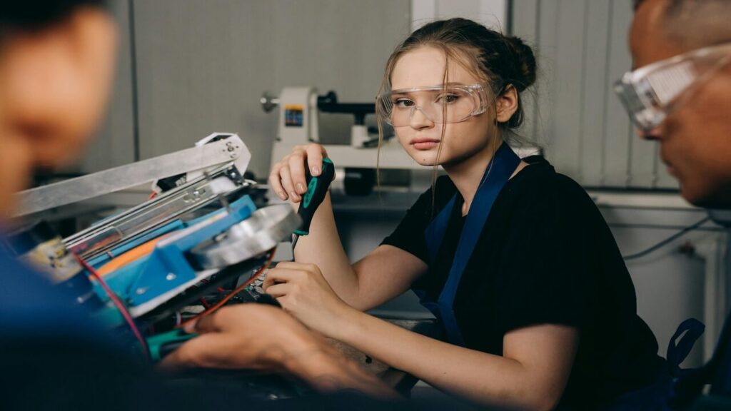 Portrait of a young female engineer in a workshop working with AI tools