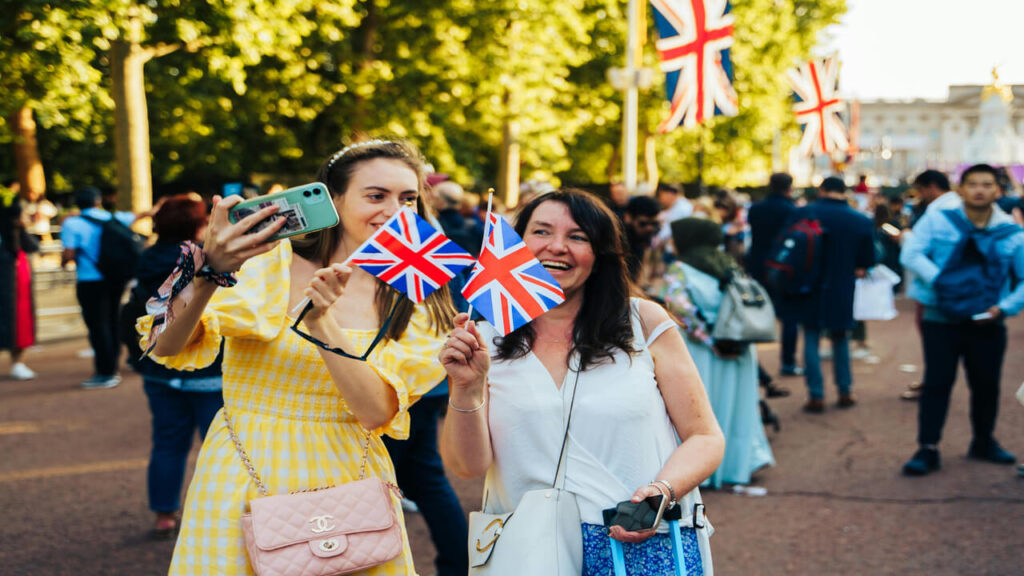 Two women celebrating in London holding Union Jacks outdoors during daylight