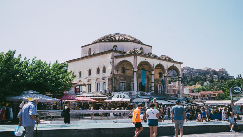 A bustling town square in Athens with a historic mosque and people strolling