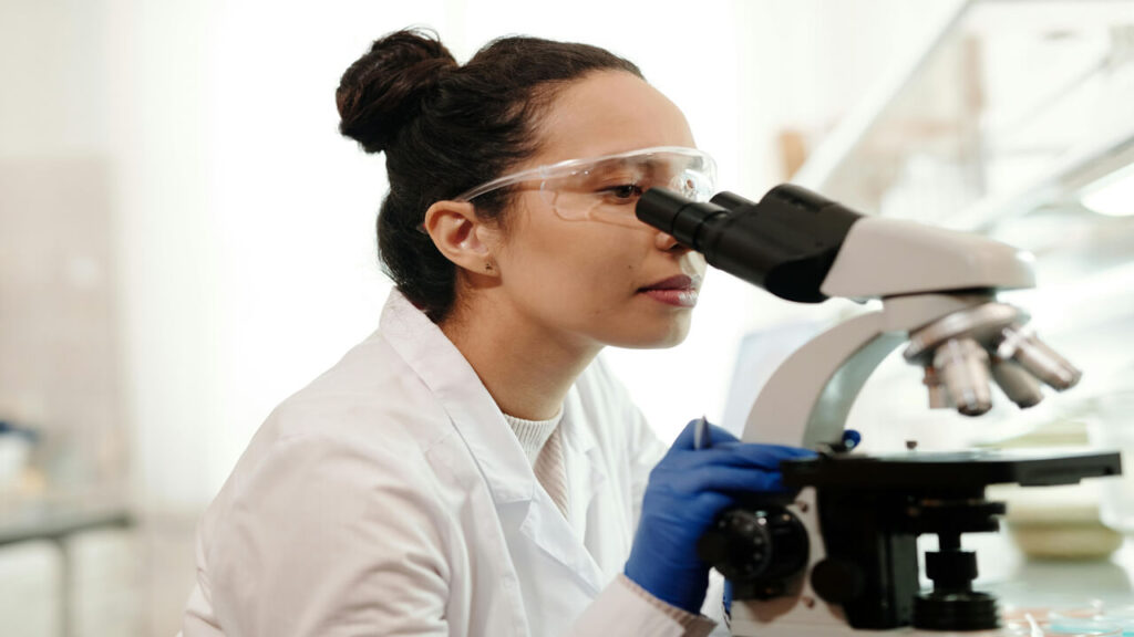 A female scientist wearing a lab coat uses a microscope for research in a laboratory setting