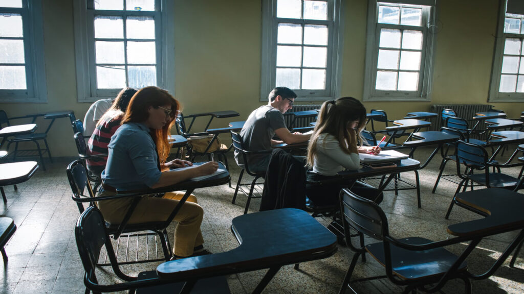A group of students focused on taking a test in a sunlit classroom setting