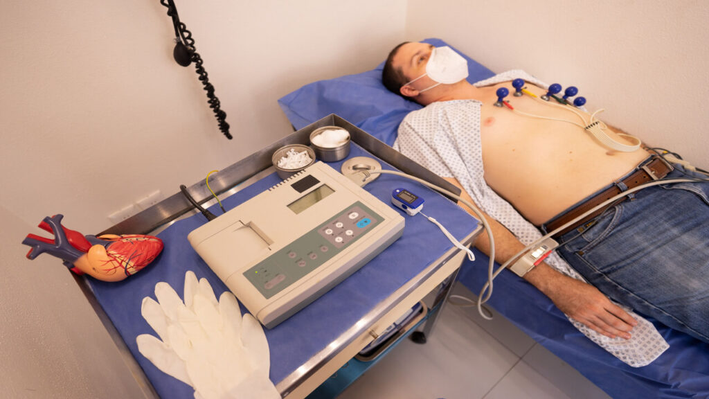 A man undergoing a cardiology exam with an ECG machine in a medical clinic