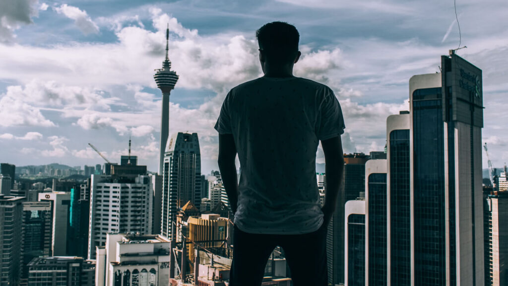 A silhouette of a man overlooking the Kuala Lumpur skyline, featuring the iconic KL Tower