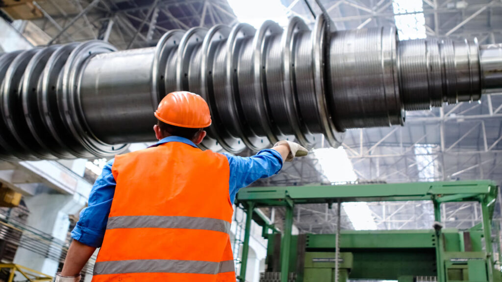 Chemical Engineer in high visibility vest and hard hat inspecting large machinery in factory setting