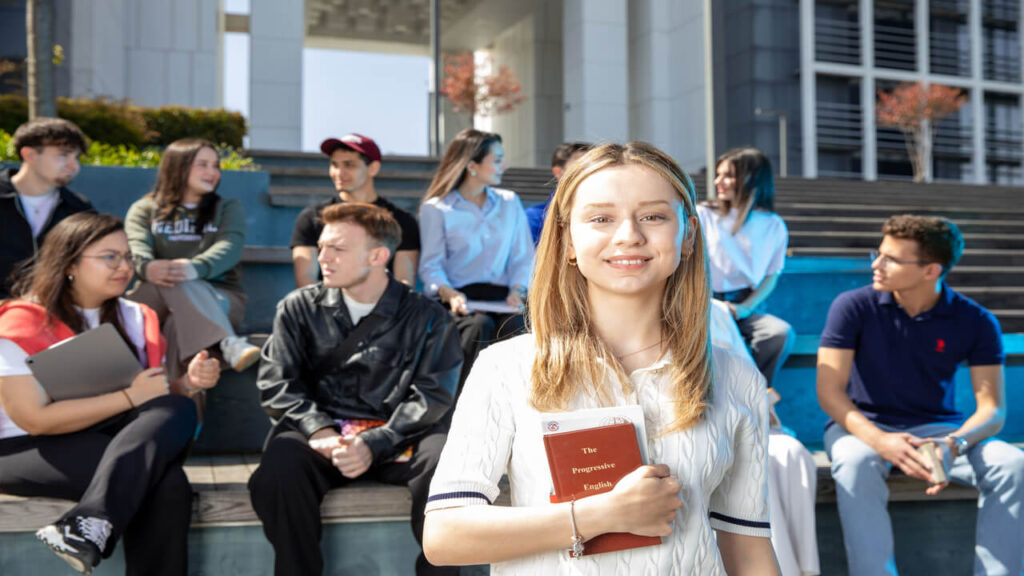 Group of young adults socializing on university steps, discussing and studying together