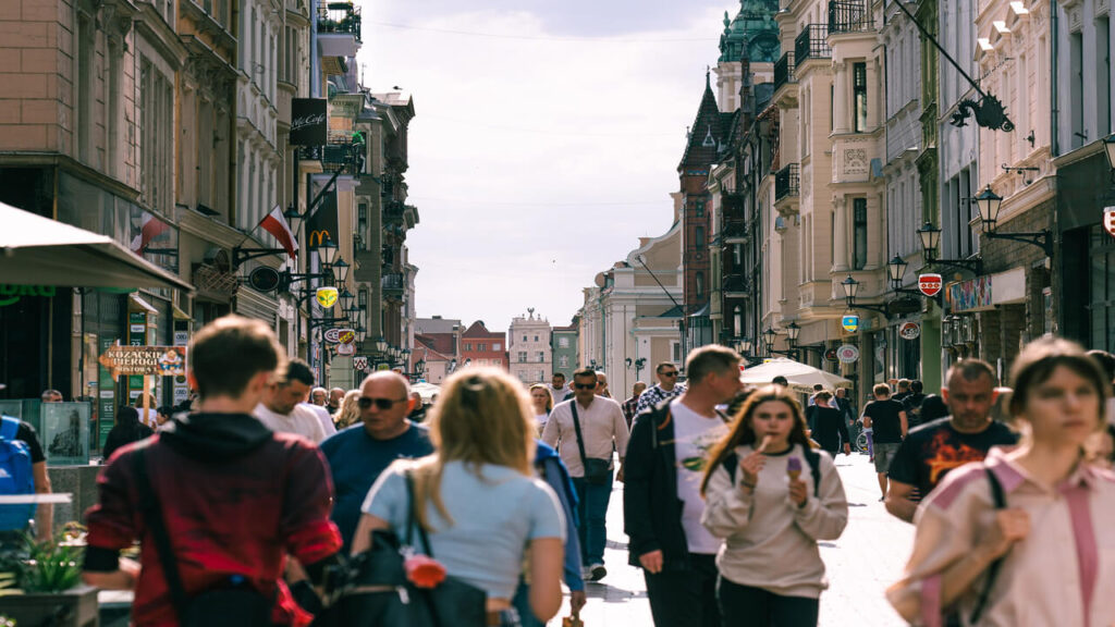 Vibrant urban street scene in Toruń, Poland, capturing people and historic architecture on a sunny day
