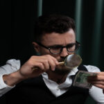 What Is Forensic Psychology-Focused adult inspecting a banknote closely with a magnifying glass indoors