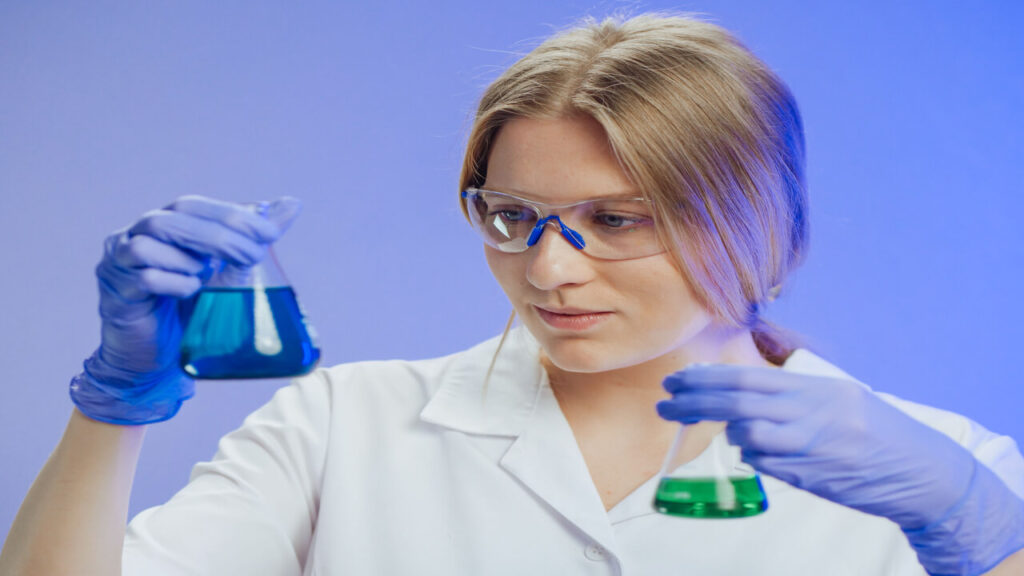 Woman engineer holding Erlenmeyer flasks with colored liquids in a laboratory