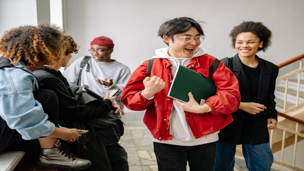 A group of diverse college students happily interacting indoors, showcasing friendship and diversity in a university setting