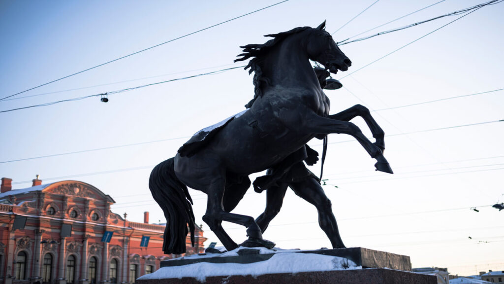 A striking silhouette of the Anichkov Bridge horse statue against a winter cityscape in Saint Petersburg, Russia