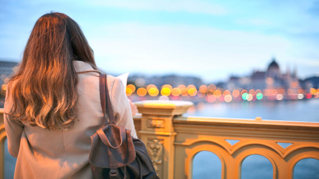 A woman enjoys a scenic view of Budapest's Danube River with bokeh lights in the background