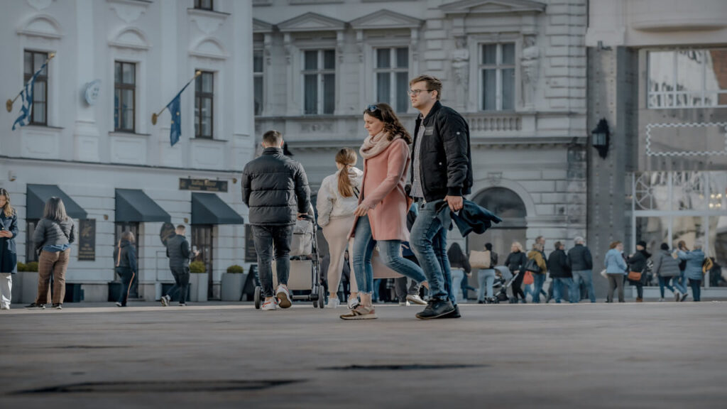 Couple walking in a busy European town square, showcasing city life and fashion